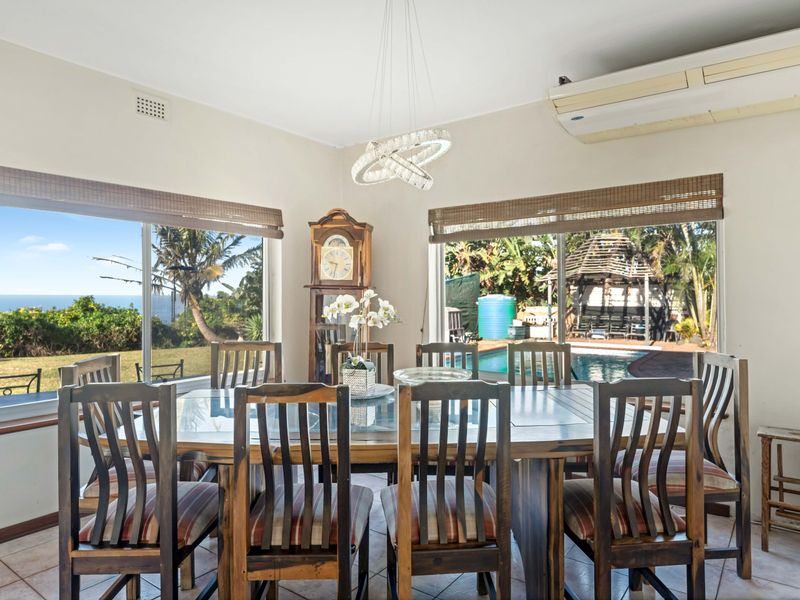 Dining room featuring tiled flooring, split system air conditioning, and large sliding glass doors providing views of the garden and pool area.