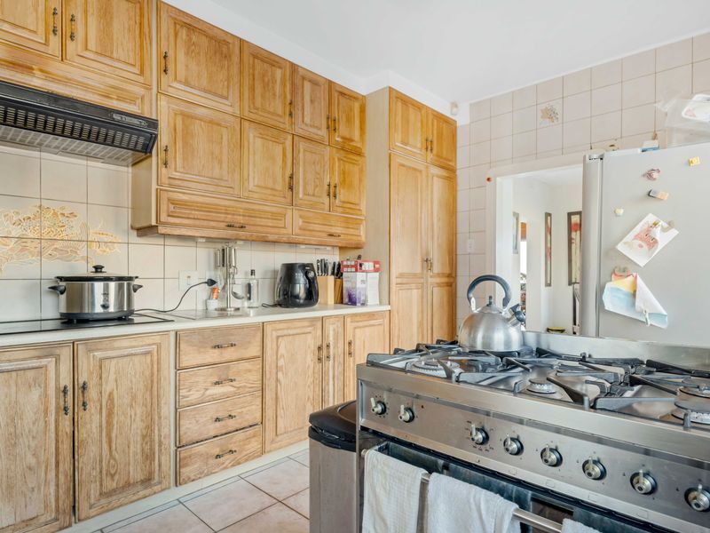 A functional kitchen featuring traditional wooden cabinetry, a gas stove, extractor fan, and tiled backsplash, offering a classic layout with ample storage space.