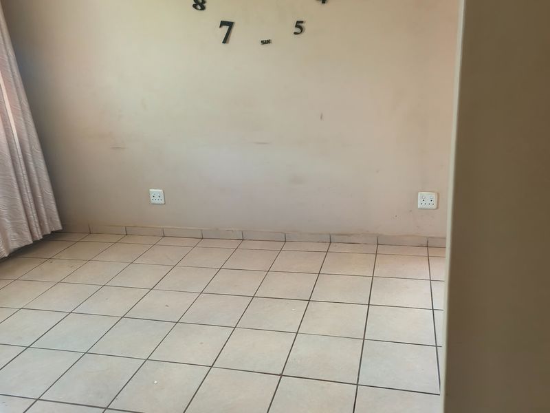 An empty living area featuring tiled flooring and neutral walls, providing a blank canvas for potential interior design and renovation.
