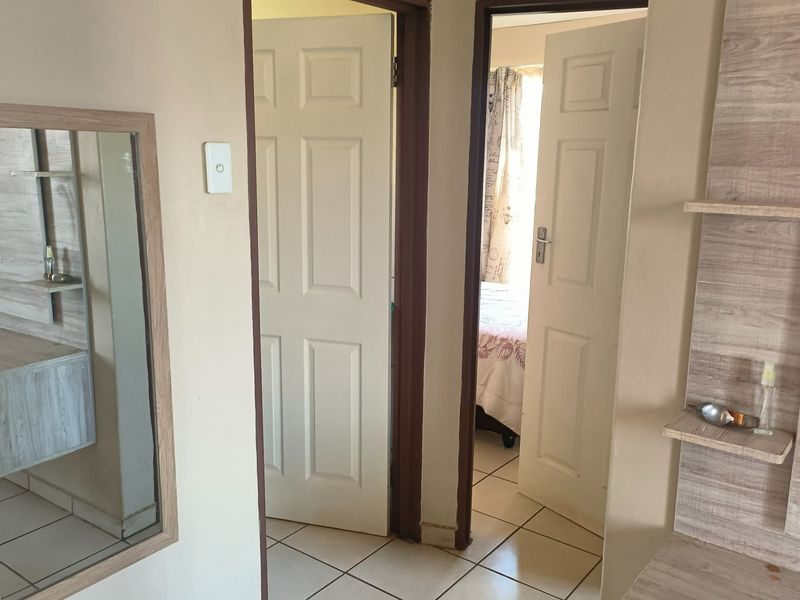 A functional hallway featuring tiled flooring and built-in shelving, providing access to adjacent rooms through standard internal doors.