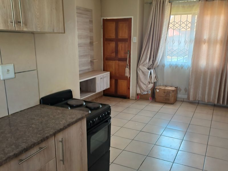 Open plan kitchen and living area featuring tiled flooring, built-in cabinetry, and a freestanding stove, offering a functional layout for daily living.
