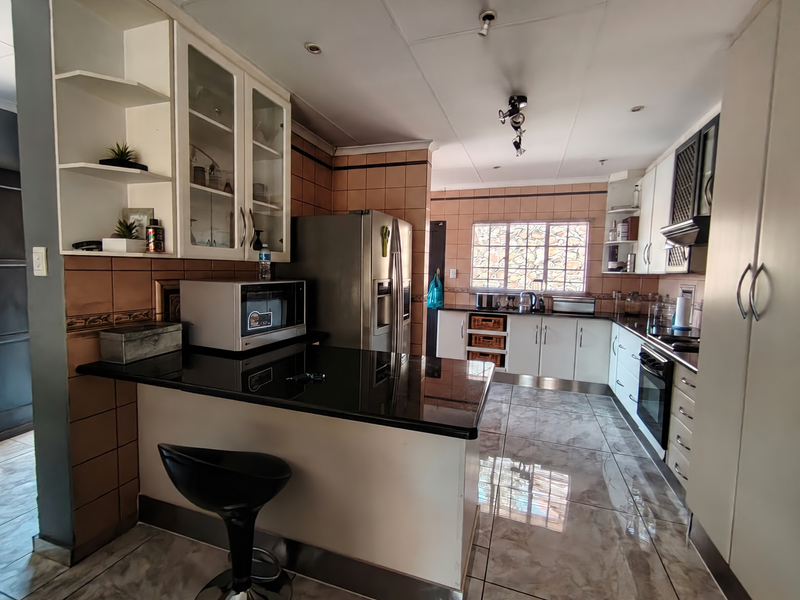 A functional kitchen featuring granite countertops, built-in cabinetry, integrated oven, and tiled finishes throughout, offering a practical layout for daily meal preparation.