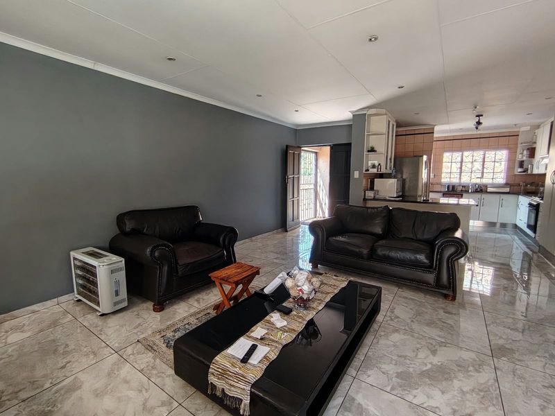 Open plan living area featuring tiled floors, recessed lighting, and a connected kitchen with built-in cabinetry and appliances.