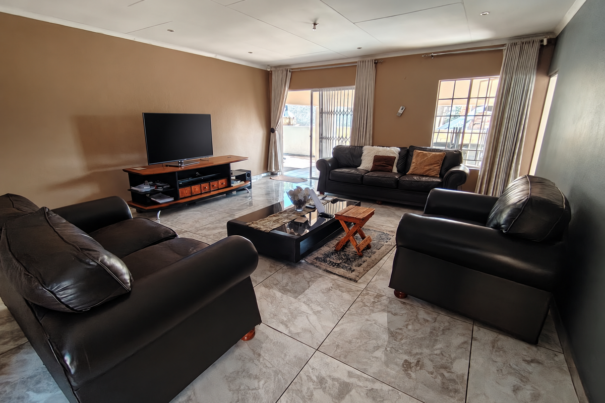 Spacious living room featuring large format tiled flooring, recessed ceiling lights, and direct access to an outdoor patio area through sliding glass doors.