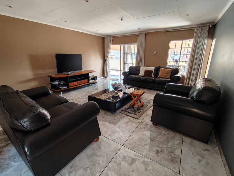 Spacious living room featuring large format tiled flooring, recessed ceiling lights, and direct access to an outdoor patio area through sliding glass doors.