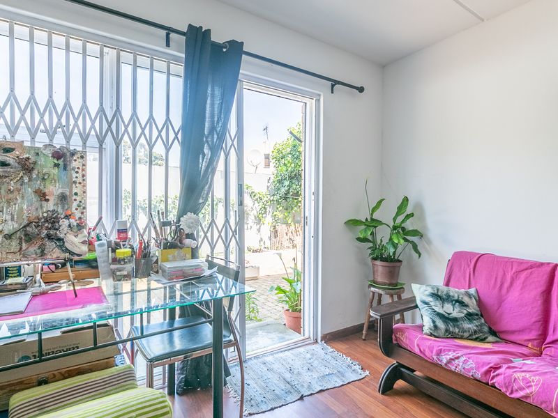 A bright living area featuring laminate flooring and a sliding glass door with a security gate, providing direct access to the outdoor space.