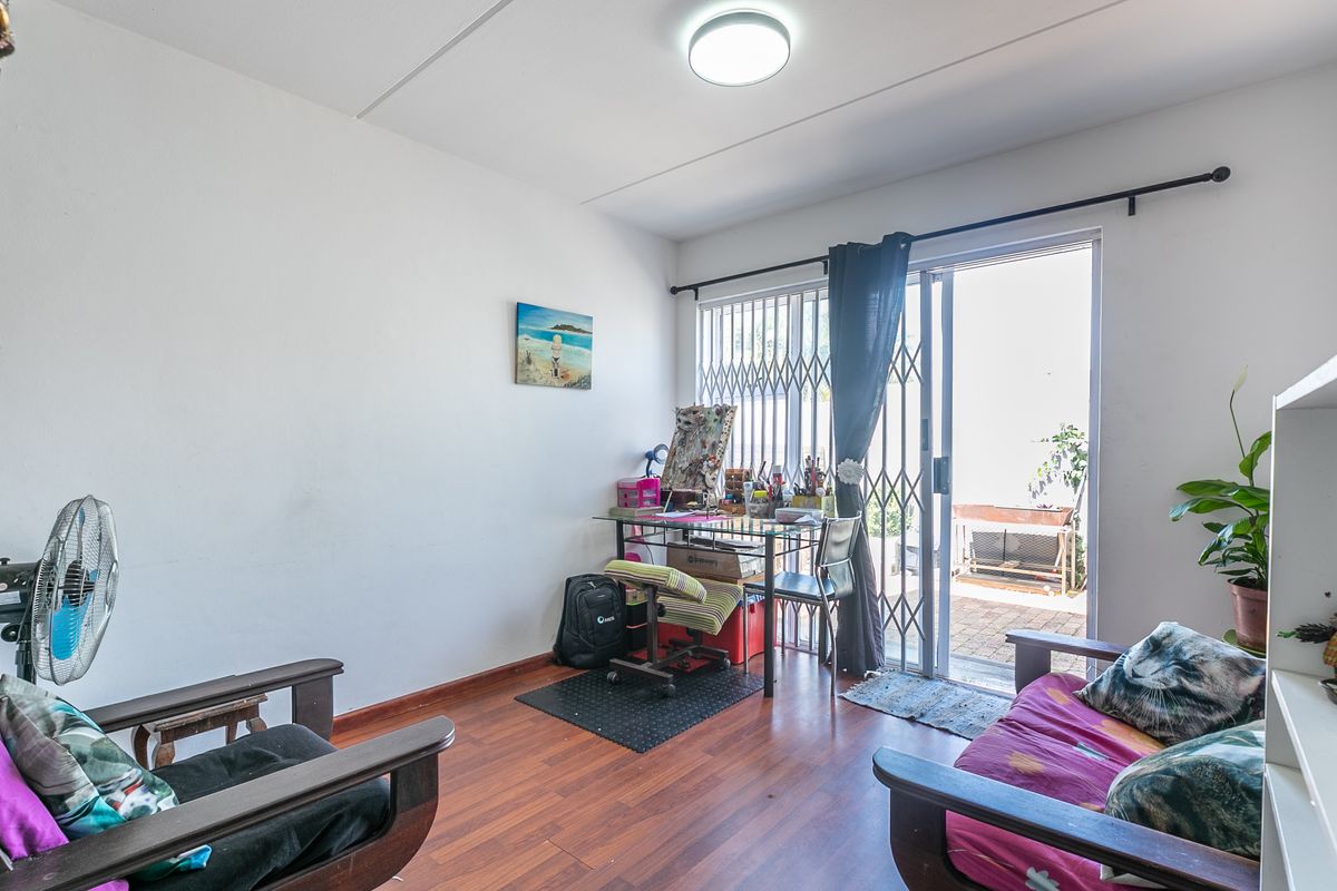 A living room featuring laminate flooring and a sliding glass door with a security gate, providing direct access to an outdoor area.