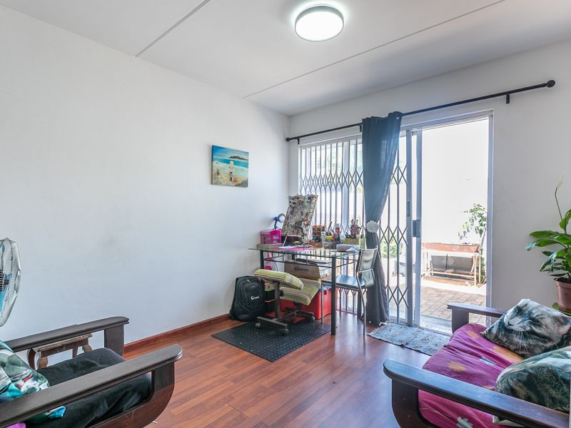 A living room featuring laminate flooring and a sliding glass door with a security gate, providing direct access to an outdoor area.