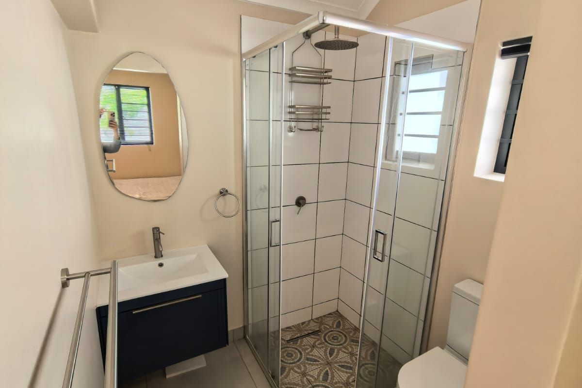 Modern bathroom featuring a glass-enclosed shower, vanity basin, toilet, and contemporary tiled finishes.