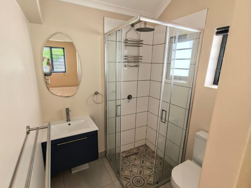 Modern bathroom featuring a glass-enclosed shower, vanity basin, toilet, and contemporary tiled finishes.