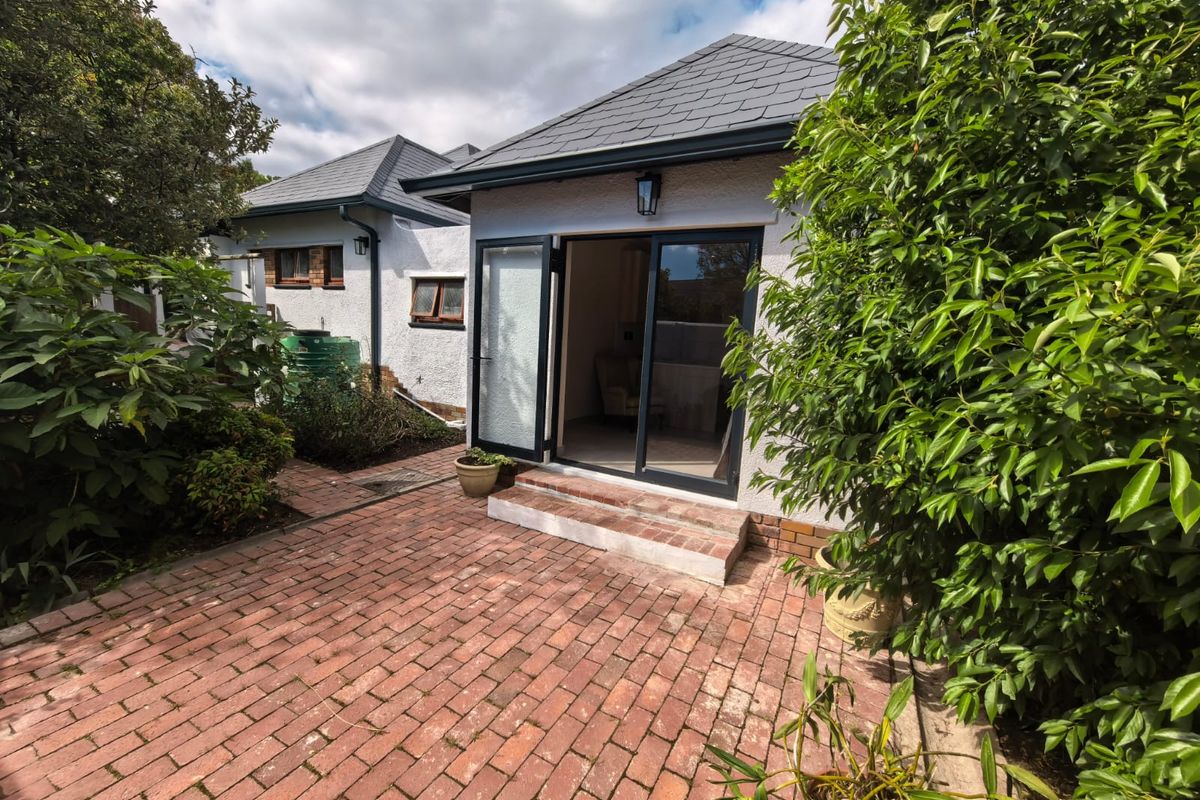 A private rear courtyard featuring a brick-paved patio area with direct access to the dwelling through double glass doors under a slate roof.