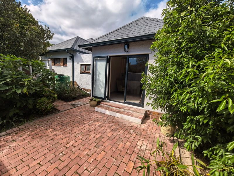 A private rear courtyard featuring a brick-paved patio area with direct access to the dwelling through double glass doors under a slate roof.