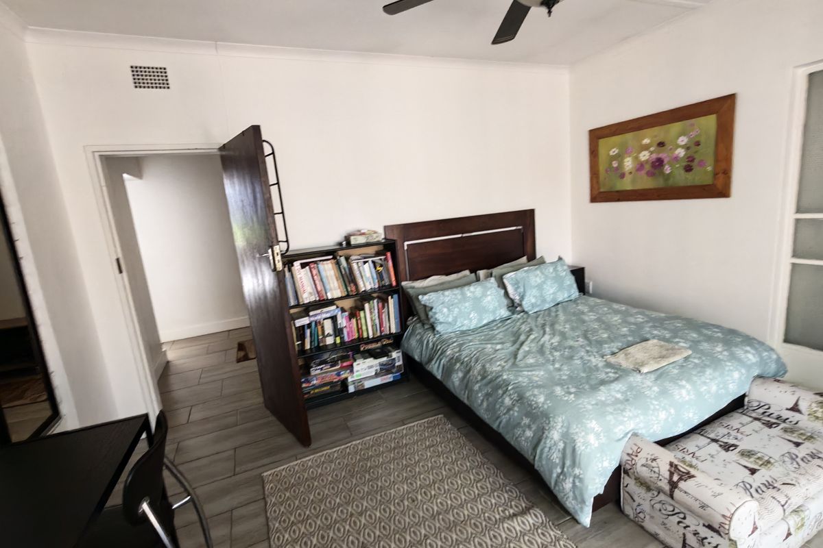 A bedroom featuring tiled flooring and a ceiling fan, providing a functional space with neutral wall finishes.