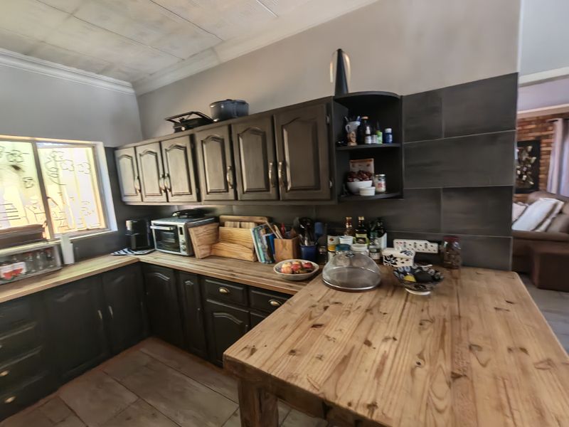 A functional kitchen featuring dark wooden cabinetry, a natural wood countertop, and a tiled splashback, offering a rustic aesthetic with potential for modernization.
