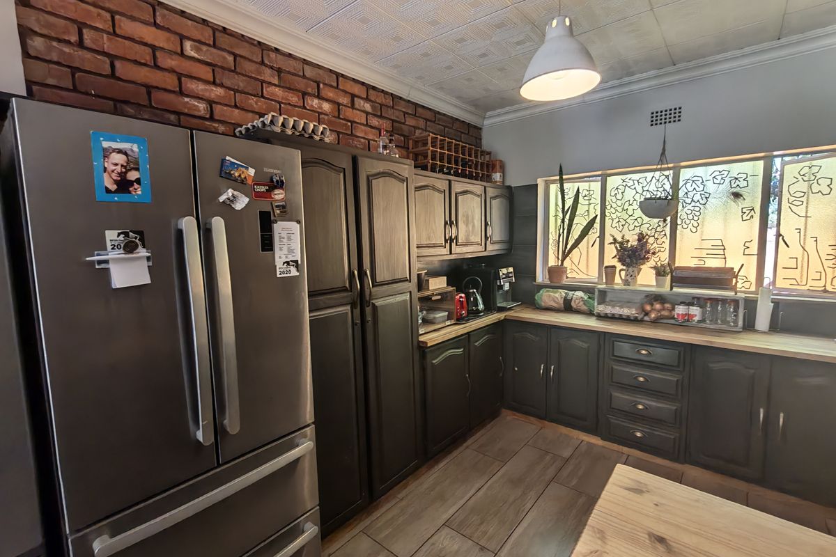A kitchen featuring exposed brick walls, dark timber cabinetry, wooden countertops, and decorative window film, offering a rustic and functional workspace.