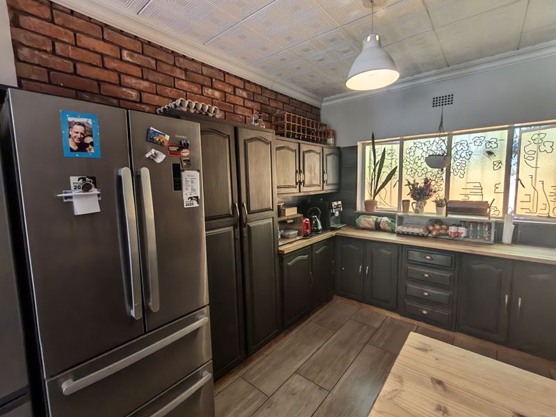 A kitchen featuring exposed brick walls, dark timber cabinetry, wooden countertops, and decorative window film, offering a rustic and functional workspace.