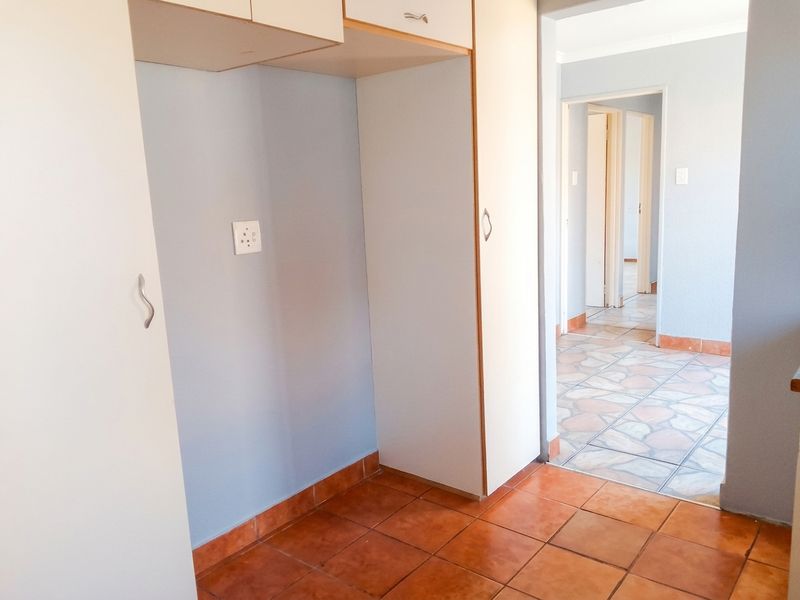 A functional hallway featuring built-in storage cupboards and durable tiled flooring, providing access to adjacent rooms within the home.