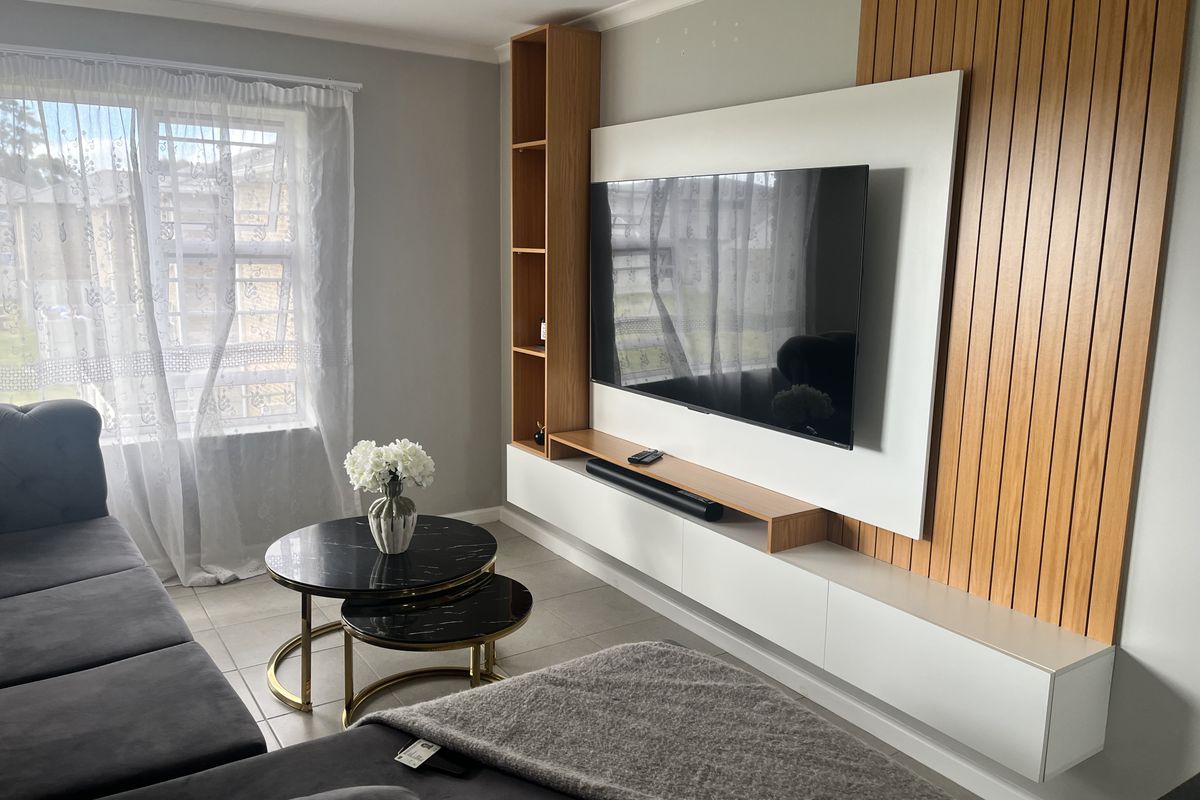 A modern living room featuring a custom built-in media unit with integrated shelving and decorative slatted wood wall paneling.