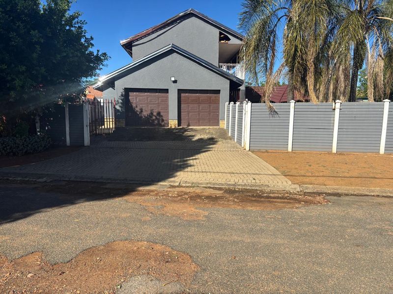 Front exterior view of a double-story house featuring a double garage, paved driveway, and perimeter fencing.