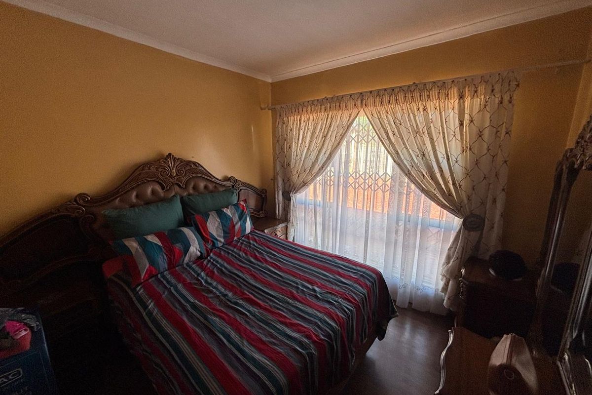A bedroom featuring laminate flooring, coved ceilings, and a security gate on the window.