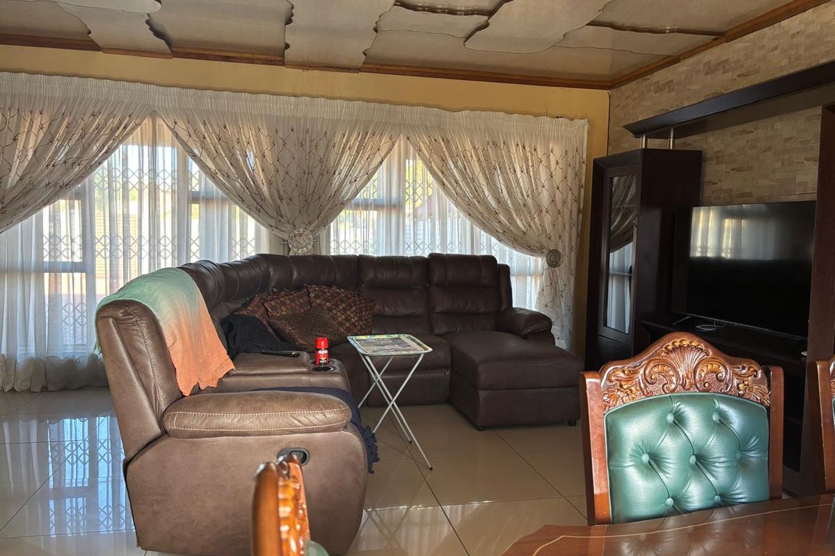 A living room featuring tiled flooring, a decorative ceiling, and a stone-cladding feature wall with integrated cabinetry.