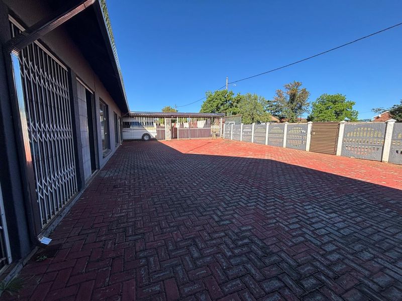 Spacious paved driveway and front courtyard area featuring secure perimeter walling and security gates.