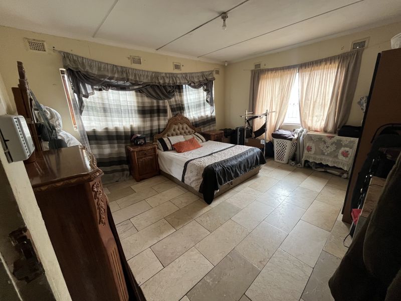 Spacious bedroom featuring large format floor tiles and multiple windows, offering a blank canvas for renovation and modernization.