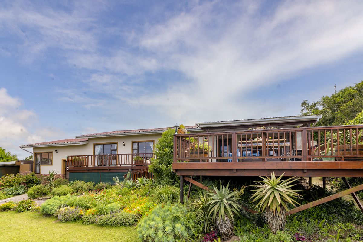 Rear view of the house featuring a spacious raised timber deck overlooking a well-maintained landscaped garden with mature plants.