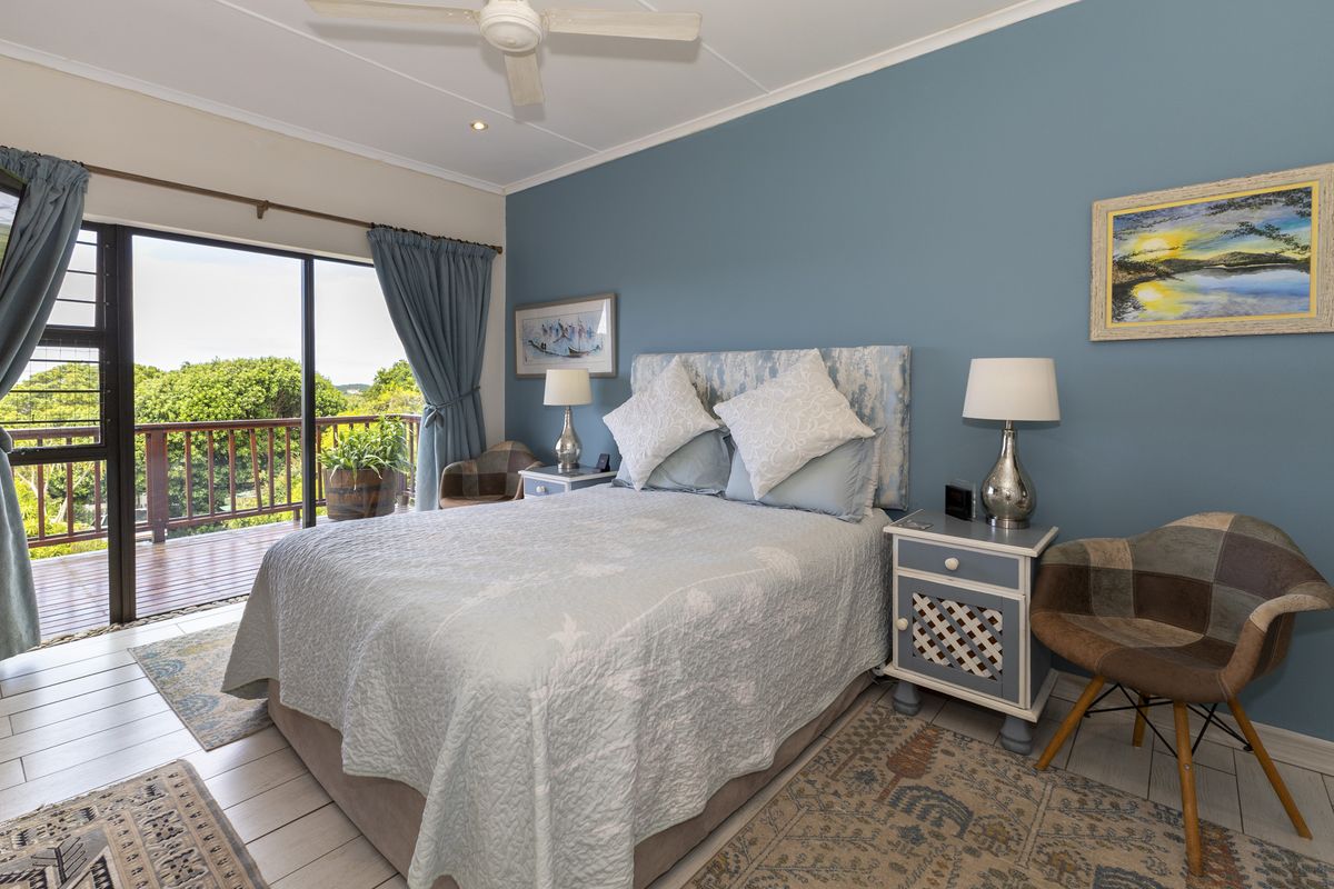 A well-maintained bedroom featuring tiled flooring, a ceiling fan, and a large sliding glass door providing access to an outdoor balcony.