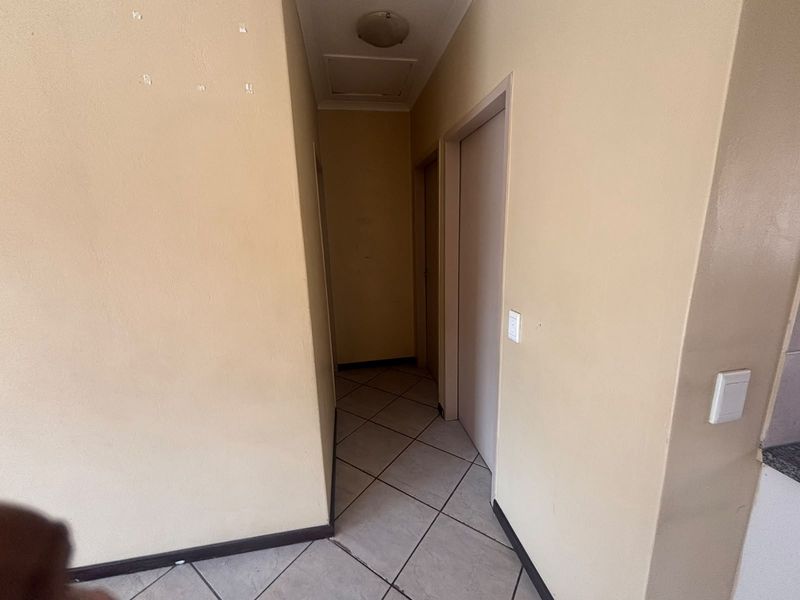 A vacant hallway featuring tiled flooring and neutral wall finishes, providing access to adjacent rooms within the flat.