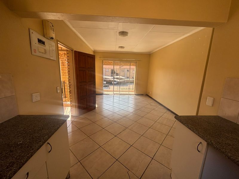 An open-plan living and kitchen area featuring tiled flooring, granite countertops, and a sliding door leading to an exterior balcony.