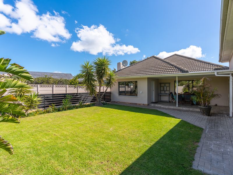 A well-maintained rear garden featuring a paved patio area, neat lawn, and secure boundary fencing, providing a pleasant outdoor living space.
