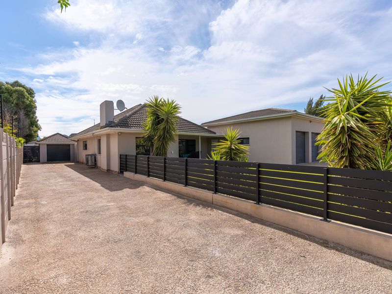 Front exterior view of the property featuring a spacious concrete driveway, double garage, and modern horizontal slat fencing.