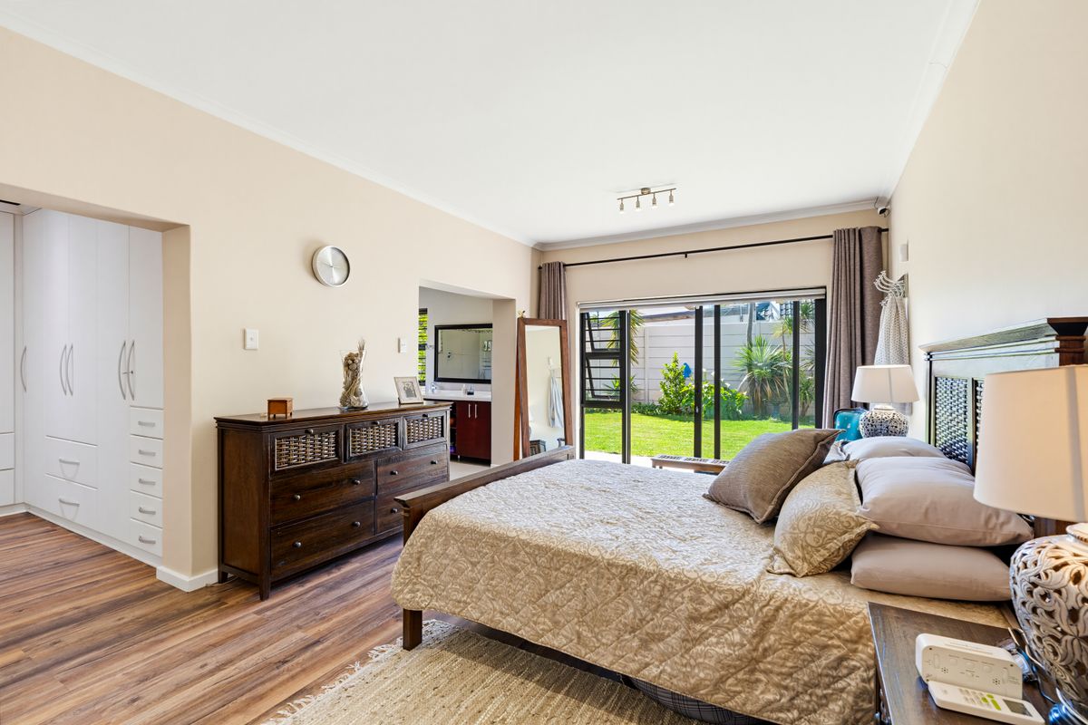 Spacious bedroom featuring laminate flooring, built-in cupboards, and large sliding glass doors providing direct access to the garden.