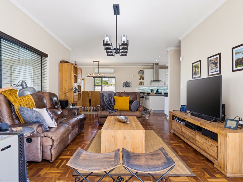 Spacious open-plan living and dining area featuring warm parquet flooring, modern lighting, and a seamless flow into the well-appointed kitchen.