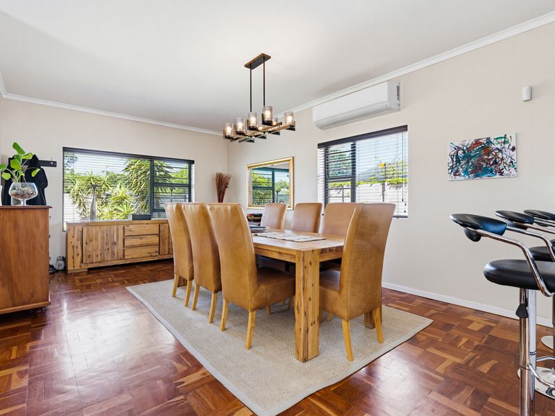 Spacious dining room featuring warm parquet flooring, modern pendant lighting, and a wall-mounted air conditioning unit, creating a comfortable and inviting atmosphere.