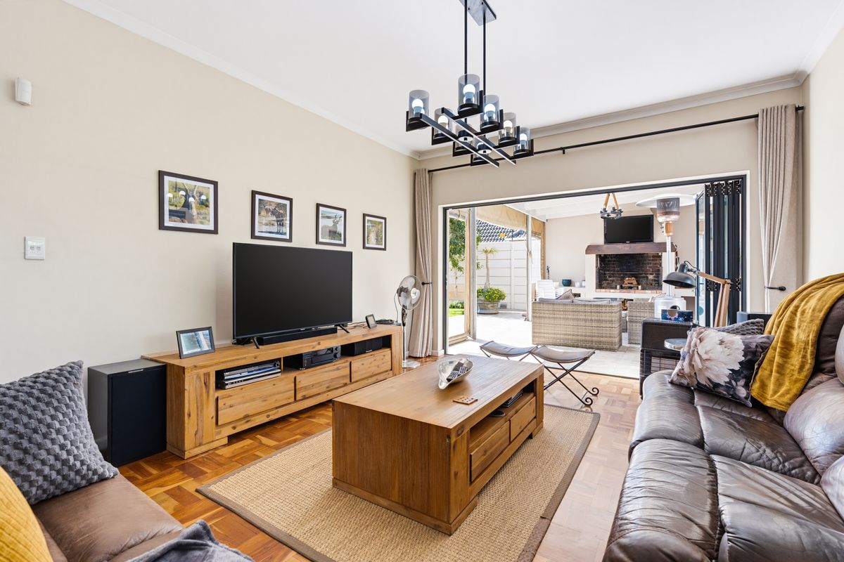 Spacious living room featuring warm parquet flooring and large stacking doors that open seamlessly to an outdoor patio area.