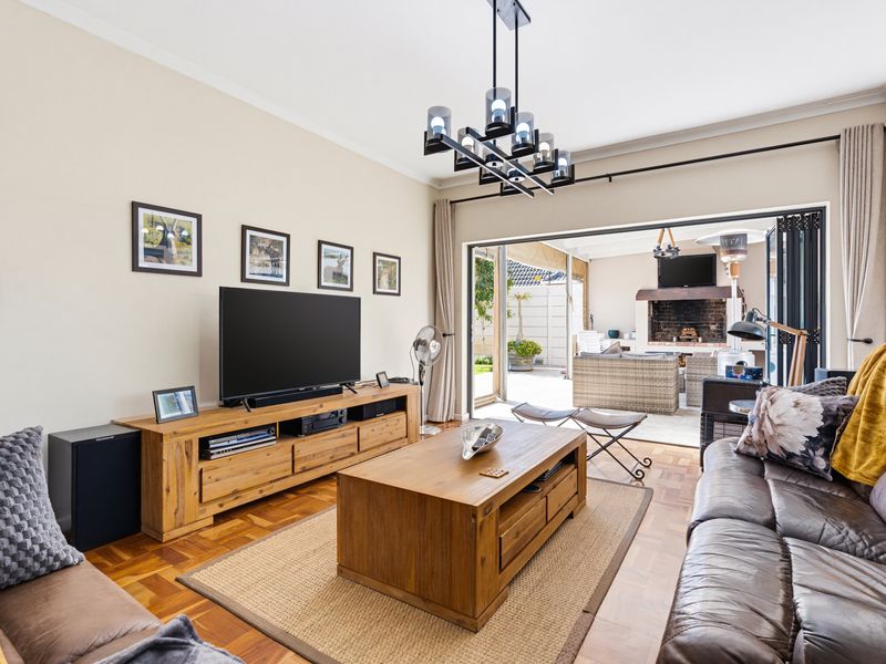 Spacious living room featuring warm parquet flooring and large stacking doors that open seamlessly to an outdoor patio area.