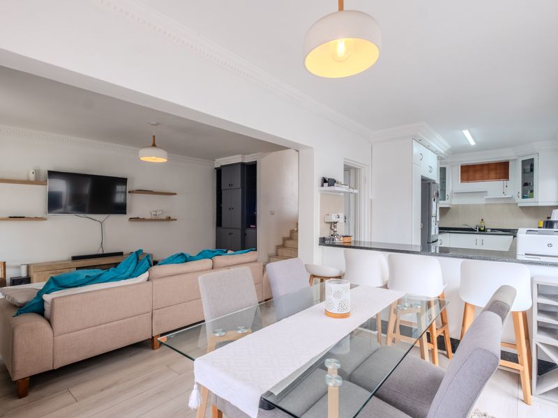 Spacious open-plan living, dining, and kitchen area featuring modern cabinetry, granite countertops, breakfast bar, and elegant crown molding throughout.