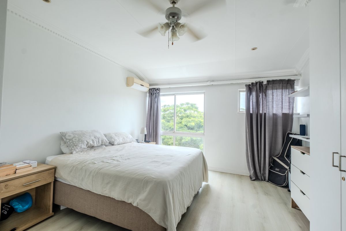 A bright bedroom featuring laminate flooring, a ceiling fan, a split-system air conditioner, and built-in wardrobe storage.