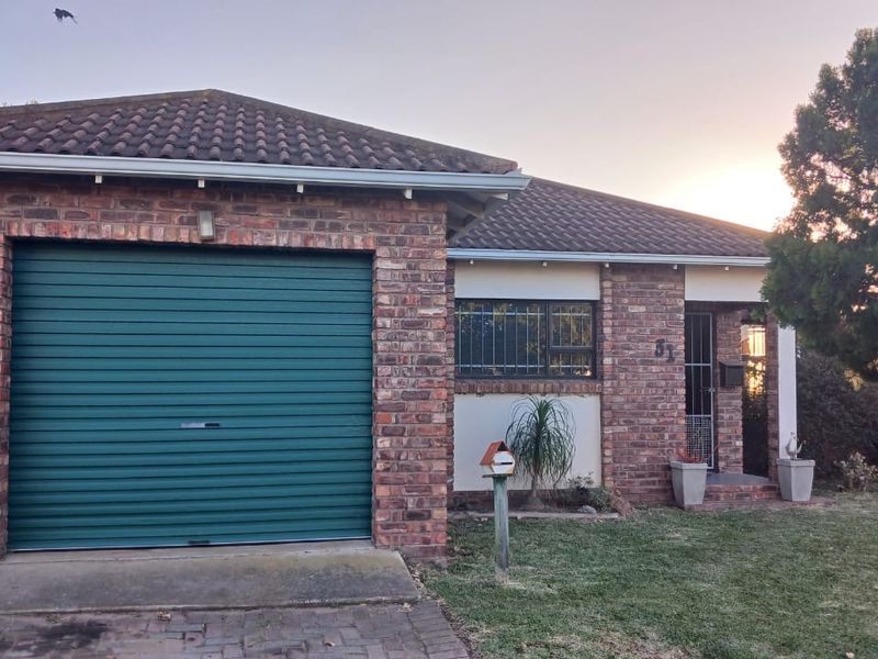 Front elevation of a face brick house featuring a single roller garage door, tiled roof, and security-fitted windows.