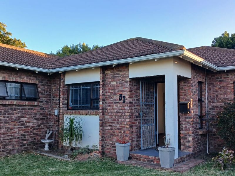 Front elevation of a face brick house featuring a tiled roof, security gate, and security bars on the windows.
