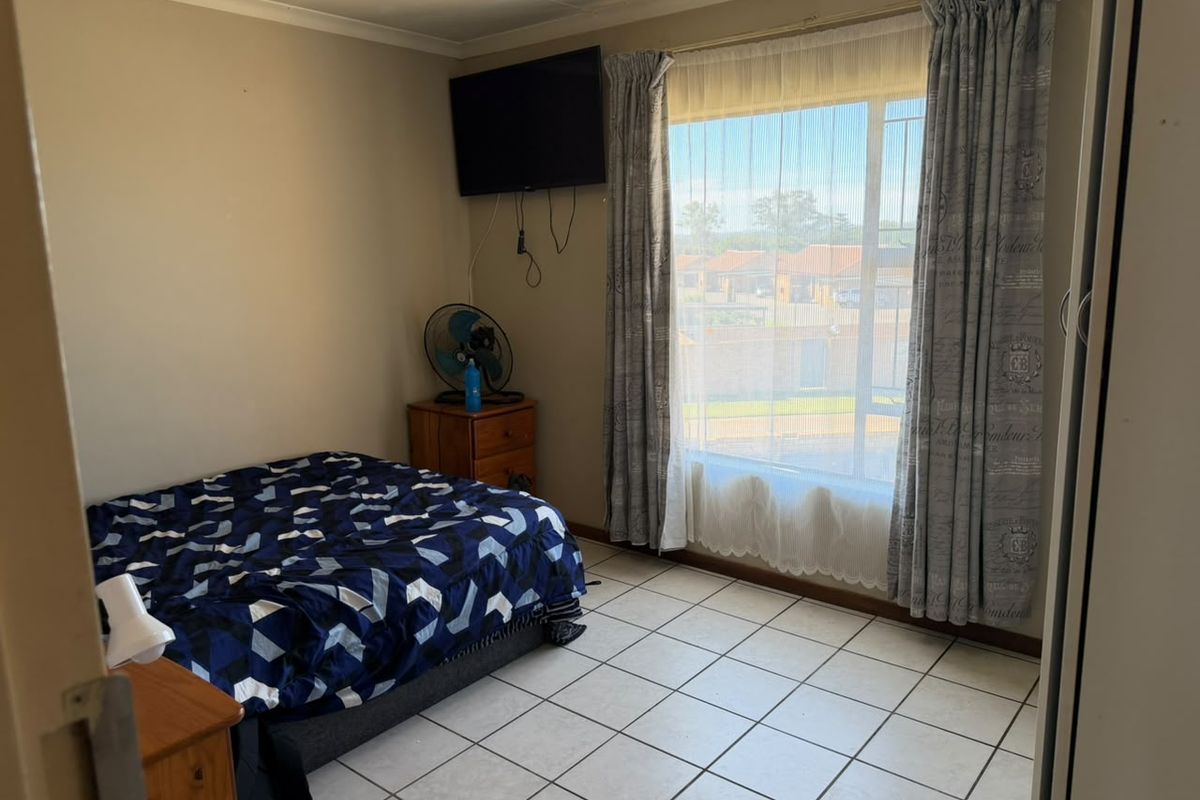 A functional bedroom featuring tiled flooring, a large window for natural light, and built-in storage space.
