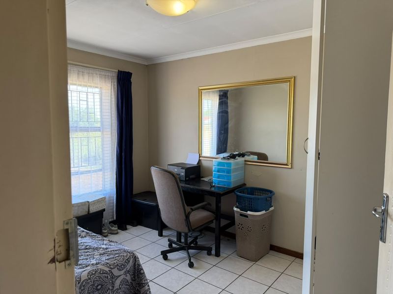 A functional bedroom featuring tiled flooring and a window with security bars, offering a neutral canvas for potential updates.