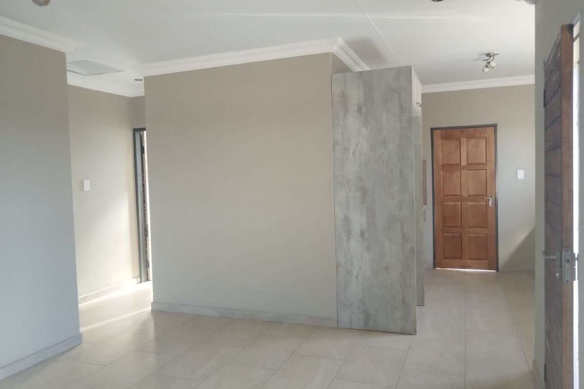 A bright, open-plan living area featuring neutral wall tones, modern tiled flooring, and clean architectural lines, ready for personalization.