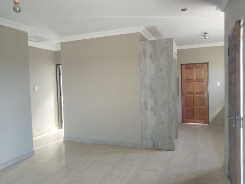 A bright, open-plan living area featuring neutral wall tones, modern tiled flooring, and clean architectural lines, ready for personalization.