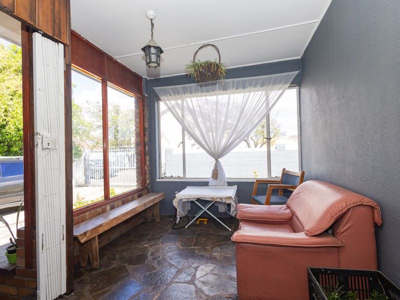 Enclosed patio area featuring stone flooring and large windows, offering a versatile space that could be updated to enhance its appeal.