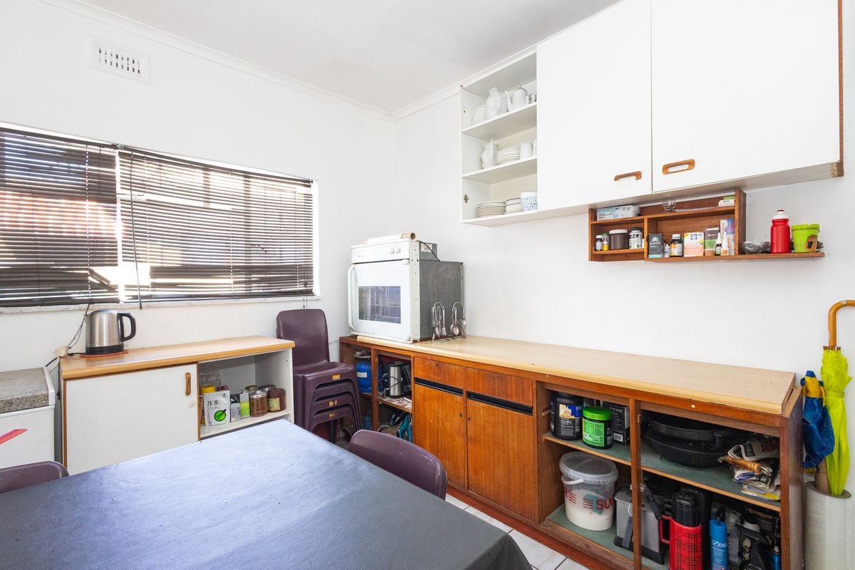 A dated kitchen area featuring original timber-look cabinetry, laminate countertops, and a wall-mounted oven, offering significant potential for modernization and renovation.