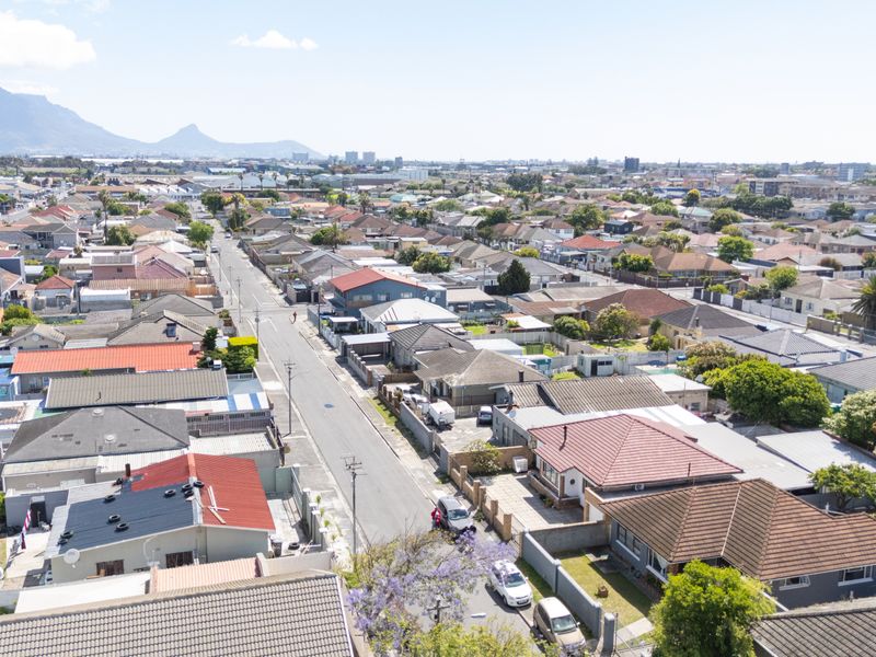 An aerial view of a residential neighbourhood with a mountain backdrop, showcasing the surrounding street layout and housing density.