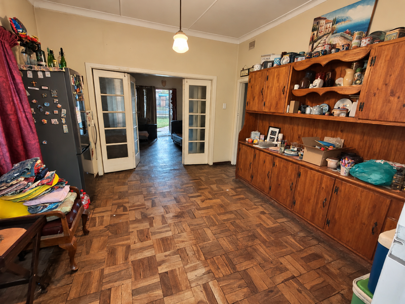 Living area featuring classic parquet flooring, extensive built-in wooden cabinetry, and double french doors leading to an adjacent space.